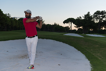 Image showing golfer hitting a sand bunker shot on sunset