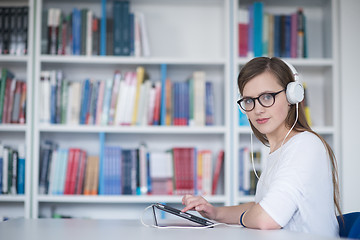 Image showing female student study in library, using tablet and searching for 