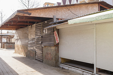 Image showing Closed trade pavilions and boarded metallosayding building a sidewalk cafe on a deserted seaside street