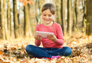 Image showing Little girl is reading from tablet