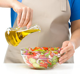 Image showing Cook is pouring olive oil into salad