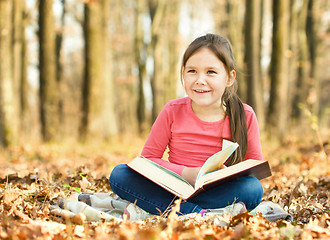 Image showing Little girl is reading a book outdoors