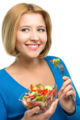 Image showing Young attractive woman is eating salad using fork