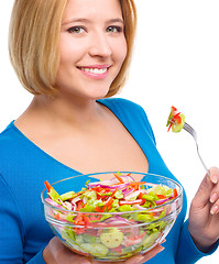 Image showing Young attractive woman is eating salad using fork