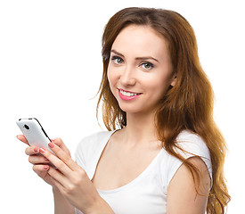 Image showing Young woman is typing sms message on her phone