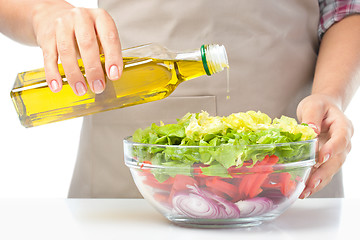 Image showing Cook is pouring olive oil into salad