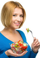 Image showing Young attractive woman is eating salad using fork