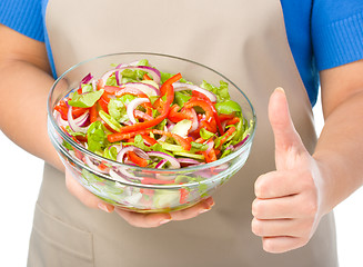 Image showing Cook is holding a big bowl with fresh salad