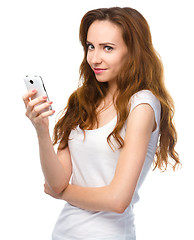 Image showing Young woman is typing sms message on her phone