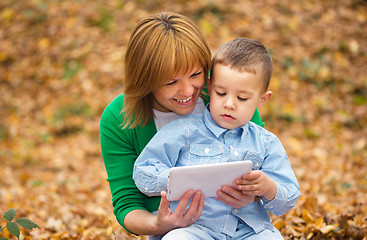 Image showing Mother is reading from tablet with her son