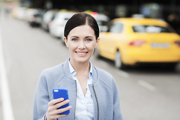 Image showing smiling woman with smartphone over taxi in city