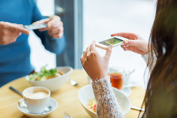 Image showing close up of couple picturing food by smartphone