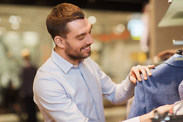 Image showing happy young man choosing clothes in clothing store