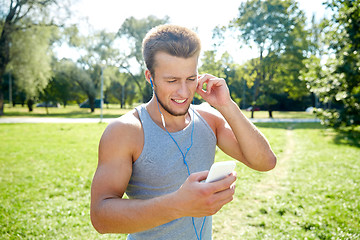 Image showing happy man with earphones and smartphone at park