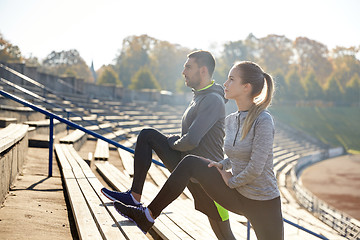 Image showing couple stretching leg on stands of stadium