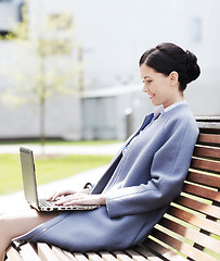 Image showing smiling business woman with laptop in city