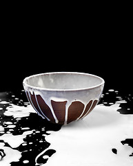 Image showing Ceramic bowl and spilled milk in black