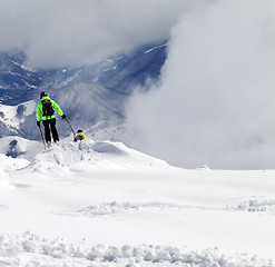 Image showing Freeriders on off-piste slope and mountains in mist