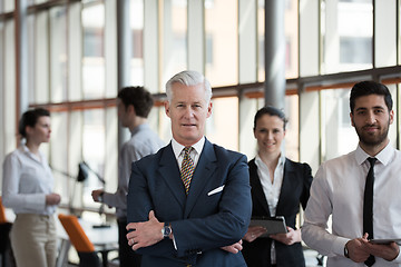 Image showing portrait of senior businessman as leader  with group of people i