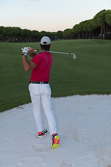 Image showing golfer hitting a sand bunker shot on sunset