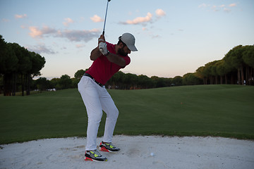 Image showing golfer hitting a sand bunker shot on sunset