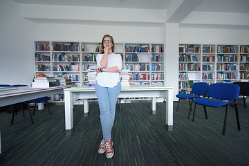 Image showing female student study in library, using tablet and searching for 