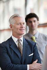 Image showing portrait of senior businessman as leader  with staff in backgrou