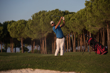 Image showing golfer hitting a sand bunker shot on sunset