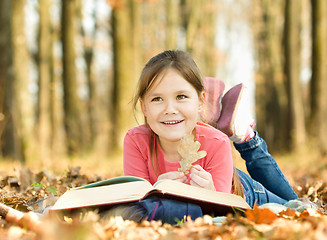 Image showing Little girl is reading a book outdoors