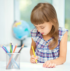 Image showing Little girl is drawing using pencils