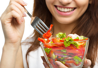 Image showing Young attractive woman is eating salad using fork