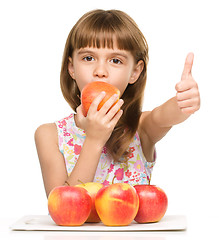 Image showing Little girl with apples is showing thumb up sign