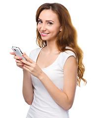 Image showing Young woman is typing sms message on her phone