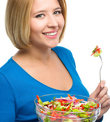 Image showing Young attractive woman is eating salad using fork