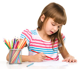 Image showing Little girl is drawing using pencils