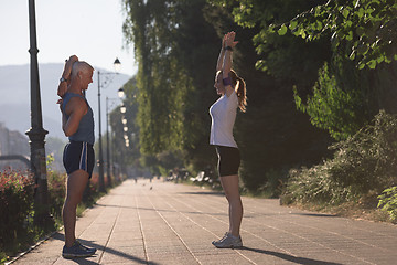 Image showing couple warming up and stretching before jogging