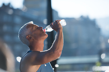 Image showing senior jogging man drinking fresh water from bottle