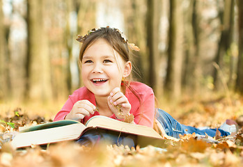 Image showing Little girl is reading a book outdoors