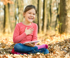 Image showing Little girl is reading a book outdoors