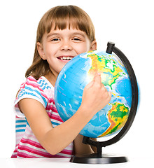 Image showing Little girl is examining globe