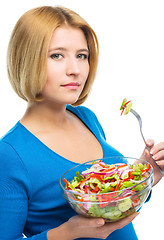 Image showing Young attractive woman is eating salad using fork