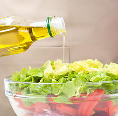 Image showing Cook is pouring olive oil into salad