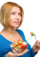 Image showing Young attractive woman is eating salad using fork