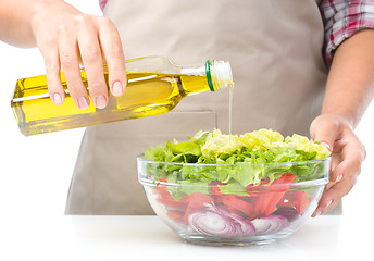 Image showing Cook is pouring olive oil into salad