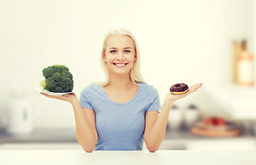 Image showing smiling woman with broccoli and donut on kitchen