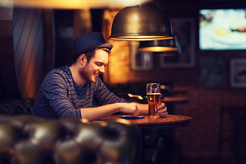 Image showing man with smartphone and beer texting at bar