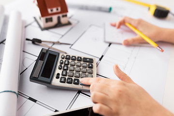 Image showing close up of architect hand counting on calculator