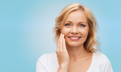 Image showing smiling woman in white t-shirt touching her face