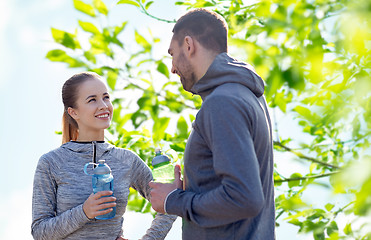 Image showing smiling couple with bottles of water outdoors