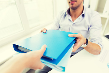 Image showing close up of businessman taking folders from hand